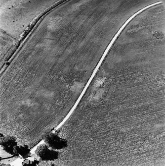 Monzie, oblique aerial view, taken from the NE, centred on the cropmarks of a moated site. The remains of a kerb cairn, and cropmarks of a barrow, are visible in the top half of the photograph.