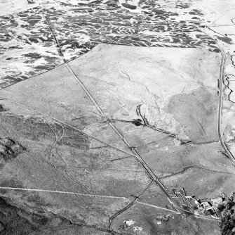 Corrymuckloch, oblique aerial view, taken from the SW, showing the Crieff to Dalnacardoch military road running across the centre of the photograph. An area of hut-circles, clearance cairns and field banks is visible in the centre left. A hoard find spot, in peat cuttings, is visible as a dark patch in the centre of the photograph.