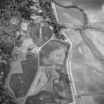 Oblique aerial view of Castle Menzies centred on a tower house, well, walled garden and military road, and the crop marks of pits, a garden and linear cropmarks, taken from the WSW.