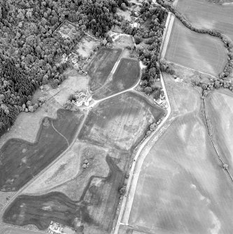 Oblique aerial view of Castle Menzies centred on a tower house, well, walled garden and military road, and the crop marks of pits, a garden and linear cropmarks, taken from the SW.