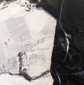 Oblique aerial view centred on the remains of the homestead and field-system with the remains of the hut-circle, homestead, building and township, taken from the NE.