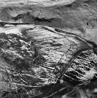 Oblique aerial view centred on the remains of the farmstead, head-dyke, field banks and rig, taken from the WNW.