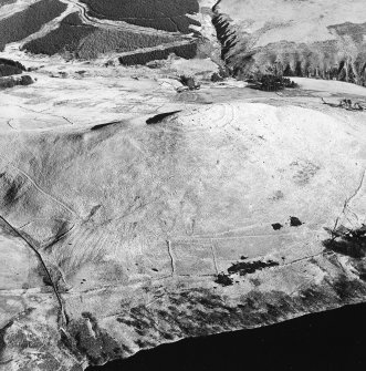 Oblique aerial view centred on the remains of a field-system and rig on the slopes below the fort, taken from the WSW.