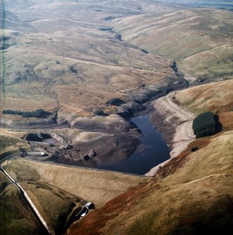 General oblique aerial view centred on the reservoir with quarry, farmsteads, enclosures, sheepfold and possible motte adjacent, taken during low water from the E.