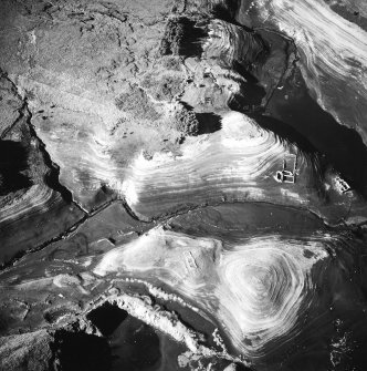 Oblique aerial view centred on the remains of the farmstead with another farmstead, sheepfold, sheep shelter, enclosures and quarry adjacent, taken from the E.