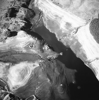 Oblique aerial view centred on the remains of farmsteads, enclosures and sheepfold with quarry and sheep shelter adjacent, taken during low water from the E.