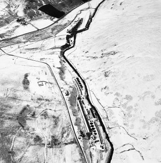 Oblique aerial view centred on the remains of buildings, enclosure, hut and lazy-beds with huts, enclosures, field-system, plantation bank, sheepfold, quarry, trackways, farmstead and field banks adjacent, taken from the WSW.