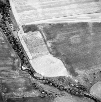 Oblique aerial view centred on the site of the enclosed cremation cemetery with the cropmarks of the enclosure adjacent, taken from the ENE.