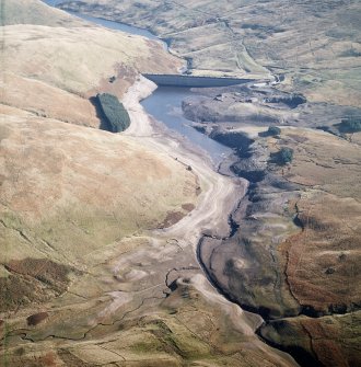 General oblique aerial view centred on the reservoir with quarry, farmsteads, enclosures, sheepfold and possible motte adjacent, taken during low water from the W.