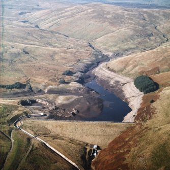 General oblique aerial view centred on the reservoir with quarry, farmsteads, enclosures, sheepfold and possible motte adjacent, taken during low water from the ESE.