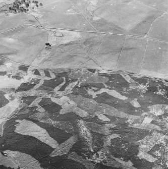 Glen Fender, oblique aerial view, taken from the WNW, centred on the footings of a building and hut. Another building and parts of a field-system are visible in the centre left of the photograph. Remains of a township and farmstead are visible in the top half.