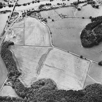 Oblique aerial view centred on the site of the castle, the cropmarks of the fort, rig and the enclosures taken from the E.