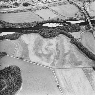 Oblique aerial view centred on the site of the castle, the cropmarks of the fort, rig and the enclosures taken from the W.