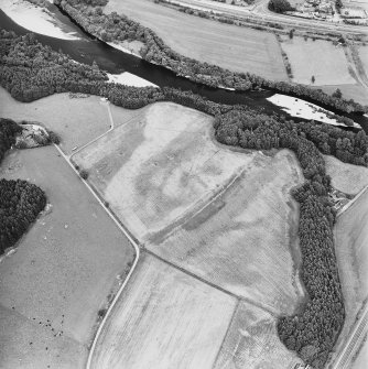 Oblique aerial view centred on the site of the castle, the cropmarks of the fort, rig and the enclosures taken from the SW.