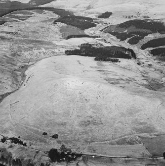 Oblique aerial view centred on the remains of the fort with a farmstead, field-system and rig on the slopes below, taken from the SW.