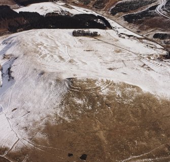 Oblique aerial view centred on the remains of the fort with field-system, rig and possible lazy-beds adjacent, taken from the SW.