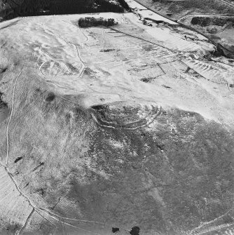 Oblique aerial view centred on the remains of the fort with field-system, rig and possible lazy-beds adjacent, taken from the WSW.