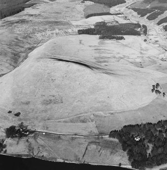 Oblique aerial view centred on the remains of the fort with a farmstead, field-systems and rig on the slopes below, taken from the SSW.