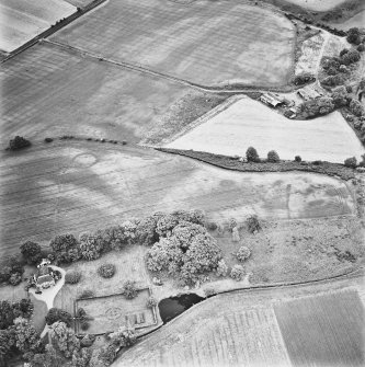 Inverdunning House and Wellhill, oblique aerial view, taken from the NE, centred on the cropmarks of enclosures, a ring-ditch, pit-circles, a pit-alignment, rig, cropmarks and pits. Inverdunning House and walled garden are visible in the bottom left-hand corner of the photograph and Wellhill farmsteading is shown in the top right-hand corner.