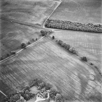 Inverdunning House, oblique aerial view, taken from the NW, centred on the cropmarks of an enclosure, pits and a ring-ditch. Inverdunning House is visible in the bottom left-hand corner of the photograph.