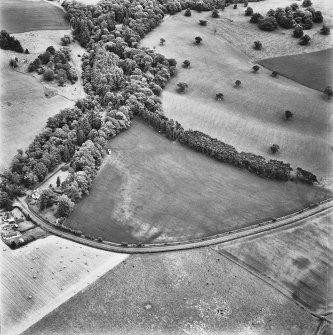 Green of Invermay, oblique aerial view, taken from the WNW, centred on the cropmarks of a palisaded enclosure, pits, enclosures, rig, a possible ring-ditch and pit-alignment. Invermay House dovecot and North Lodge and Green of Invermay House are visible in the centre left half of the photograph.