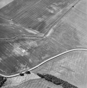 Oblique aerial view centred on the cropmarks of the pits, rig and enclosure, taken from the E.