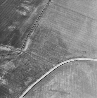 Oblique aerial view centred on the cropmarks of the pits, rig and enclosure, taken from the ESE.