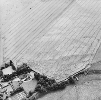 Oblique aerial view centred on the cropmarks of the enclosures with the manse adjacent, taken from the W.