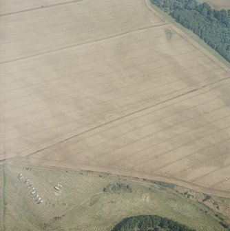 Oblique aerial view in hazy conditions centred on the cropmarks of the enclosure, with the cropmarks of the henges, possible henge, barrows, square barrows, cemetery, pit-alignments, enclosures, ring-ditch and other cropmarks adjacent, taken from the WSW.