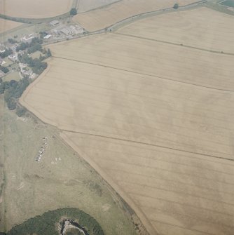 Oblique aerial view in hazy conditions centred on the cropmarks of the enclosure, with the cropmarks of the henges, possible henge, barrows, square barrows, cemetery, pit-alignments, enclosures, ring-ditch and other cropmarks adjacent, taken from the SW.