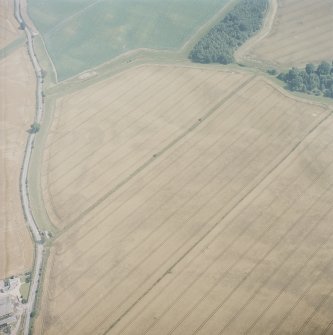 Oblique aerial in hazy conditions view centred on the cropmarks of the enclosure, barrows, square barrows, cemetery, pit-alignments and other cropmarks, taken from the W.