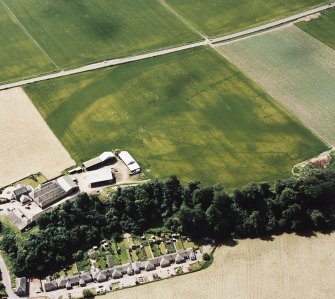 Oblique aerial view centred on the cropmarks of an enclosure, pit-circle, Roman Road, linear cropmarks, pits and pit-alignment with linear cropmarks adjacent, taken from the NNE.