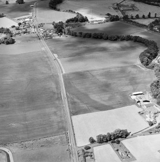 Oblique aerial view centred on the cropmarks of an enclosure, pit-circle, Roman Road, linear cropmarks, pits and pit-alignment with linear cropmarks adjacent, taken from the E.