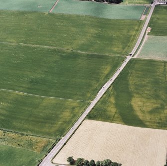 Oblique aerial view centred on linear cropmarks with further linear cropmarks, pit-alignment and Roman Road adjacent, taken from the ENE.