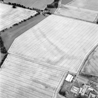 Oblique aerial view centred on the cropmarks of the possible enclosure, souterrain and ring-ditch with the stable block adjacent, taken from the SSE.