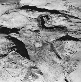 Oblique aerial view centred on the remains of rig and enclosure with fort, hut-circles, cairn, enclosures, building and rig adjacent, taken from the SSW.