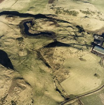 Oblique aerial view centred on the remains of the enclosure with fermtoun, rig, enclosures, hut-circles and building adjacent, taken from the SW.