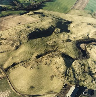 Oblique aerial view centred on the remains of rig and enclosures with fort, hut-circles, cairn, building, enclosure, rig and fermtoun adjacent, taken from the ESE.