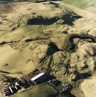 Oblique aerial view centred on the remains of rig and enclosures with fort, hut-circles, cairn, building, enclosure, rig and fermtoun adjacent, taken from the E.