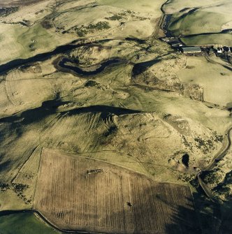 Oblique aerial view centred on the remains of the fort, hut-circles, cairn and building with rig, enclosures, hut-circles and fermtoun adjacent, taken from the WSW.