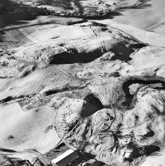 Oblique aerial view centred on the remains of rig and enclosures with fort, hut-circles, cairn, building, enclosure, rig and fermtoun adjacent, taken from the ESE.