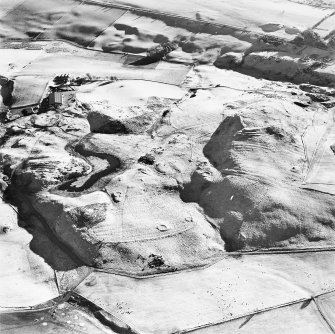 Oblique aerial view centred on the remains of rig and enclosures with fort, hut-circles, cairn, building, enclosure, rig and fermtoun adjacent, taken from the NNW.