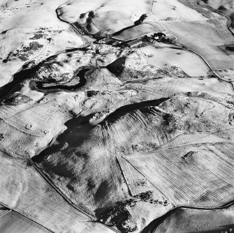 Oblique aerial view centred on the remains of rig and enclosures with fort, hut-circles, cairn, building, enclosure, rig and fermtoun adjacent, taken from the WNW.