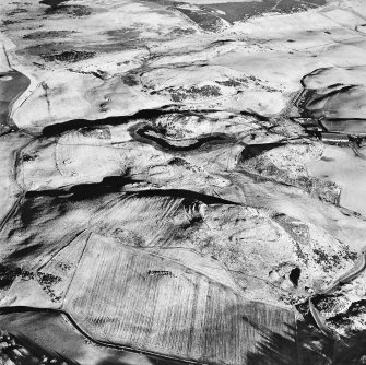 Oblique aerial view centred on the remains of rig and enclosures with fort, hut-circles, cairn, building, enclosure, rig and fermtoun adjacent, taken from the WSW.