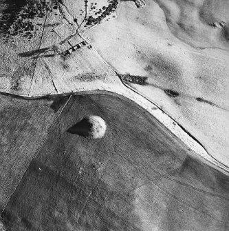 Oblique aerial view centred on the remains of the cairn with farmstead adjacent, taken from the WNW.