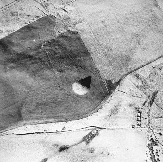Oblique aerial view centred on the remains of the cairn with farmstead adjacent, taken from the SSE.