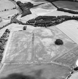 Oblique aerial view centred on the cropmarks of an enclosure and trackways with round house, enclosure, pits, cultivation remains, pit-alignment and long barrow adjacent, taken from the WNW.