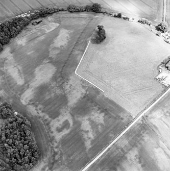 Oblique aerial view centred on the cropmarks of an unenclosed settlement with natural feature adjacent, taken from the SSW.