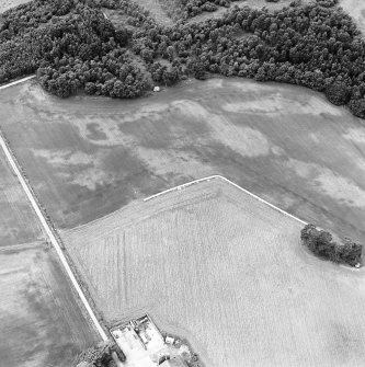 Oblique aerial view centred on the cropmarks of an unenclosed settlement with natural feature adjacent, taken from the E.