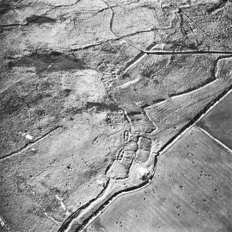 Oblique aerial view centred on the remains of the fermtoun with the remains of the buildings, hut circles and burnt mound, taken from the W.